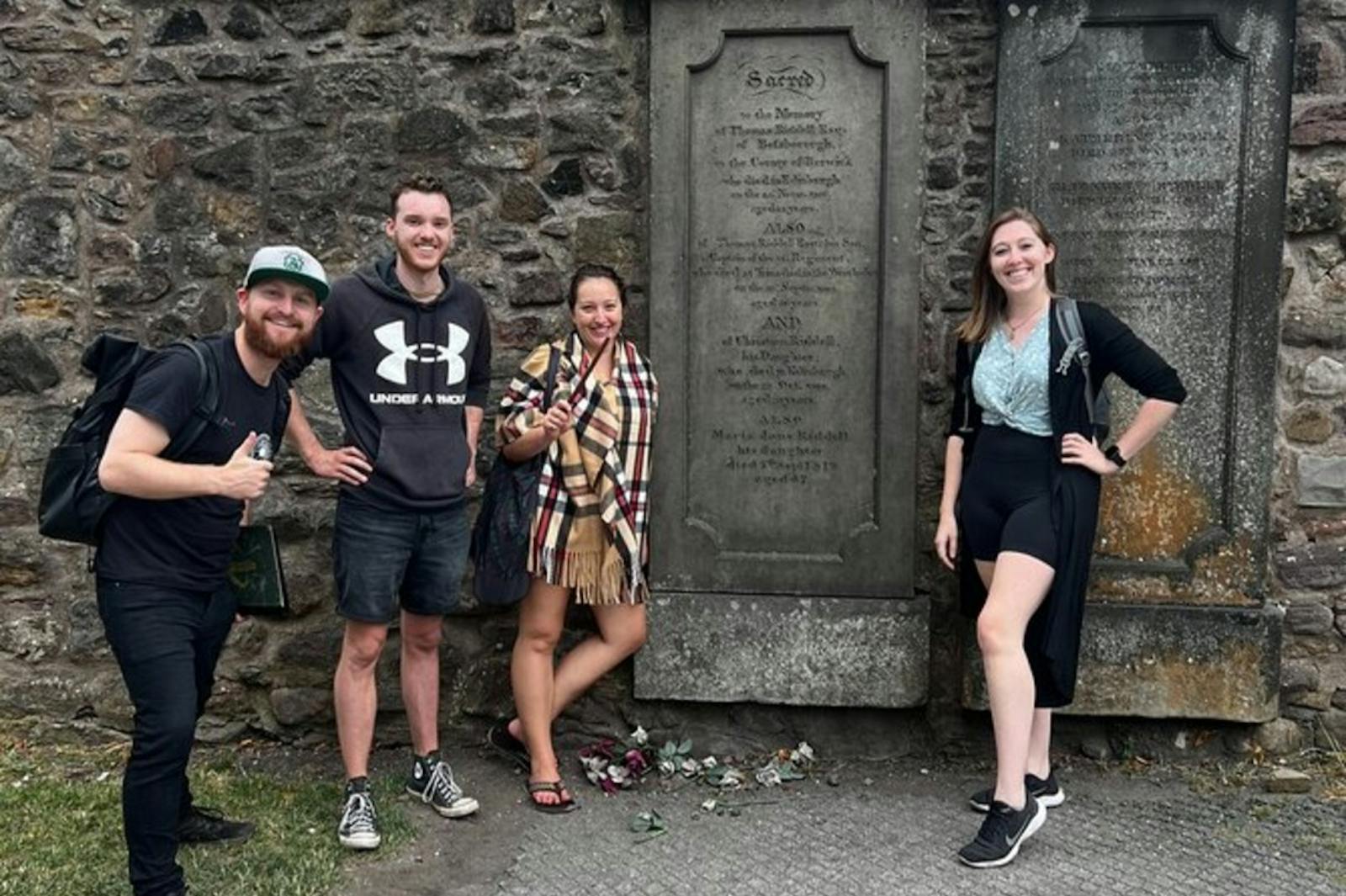 Quatre touristes souriants devant les pierres du Château d'Édimbourg